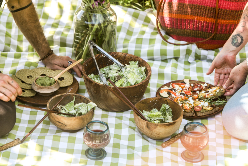 Assortment of plant based foods set out on a table cloth on the ground for a picnic